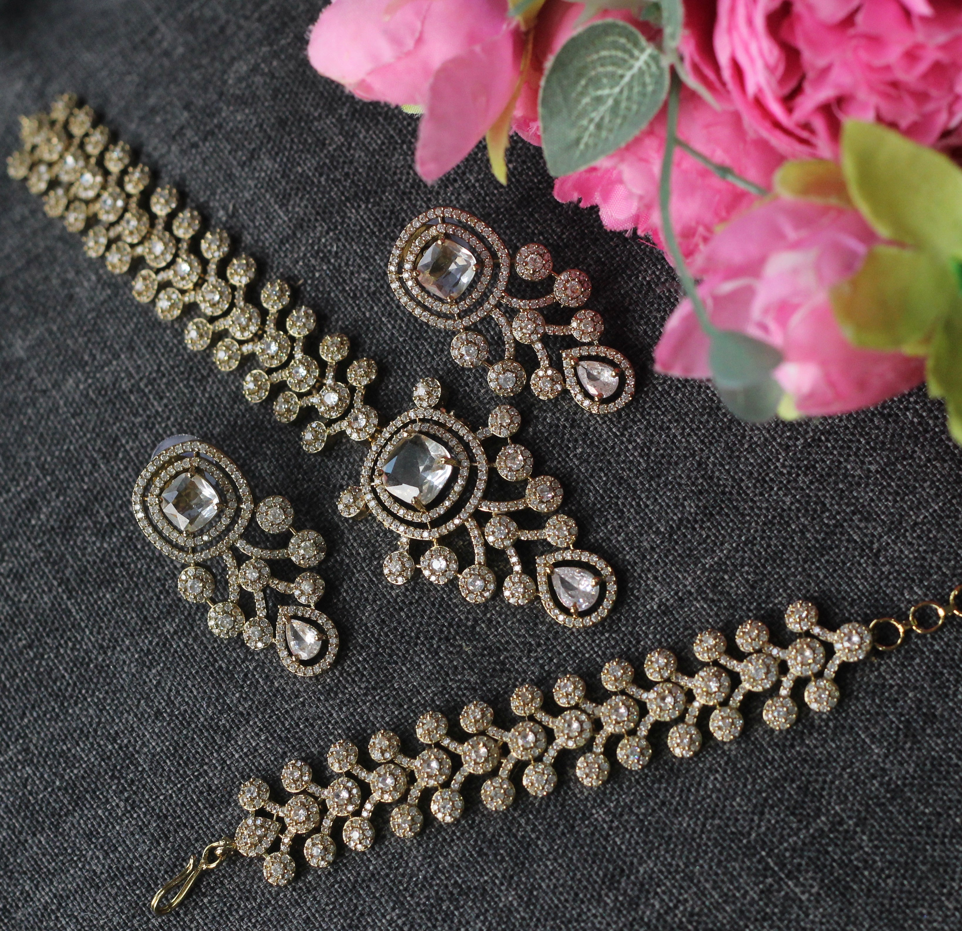 Gold-toned jewelry set with a bracelet, necklace, and earrings featuring clear stones