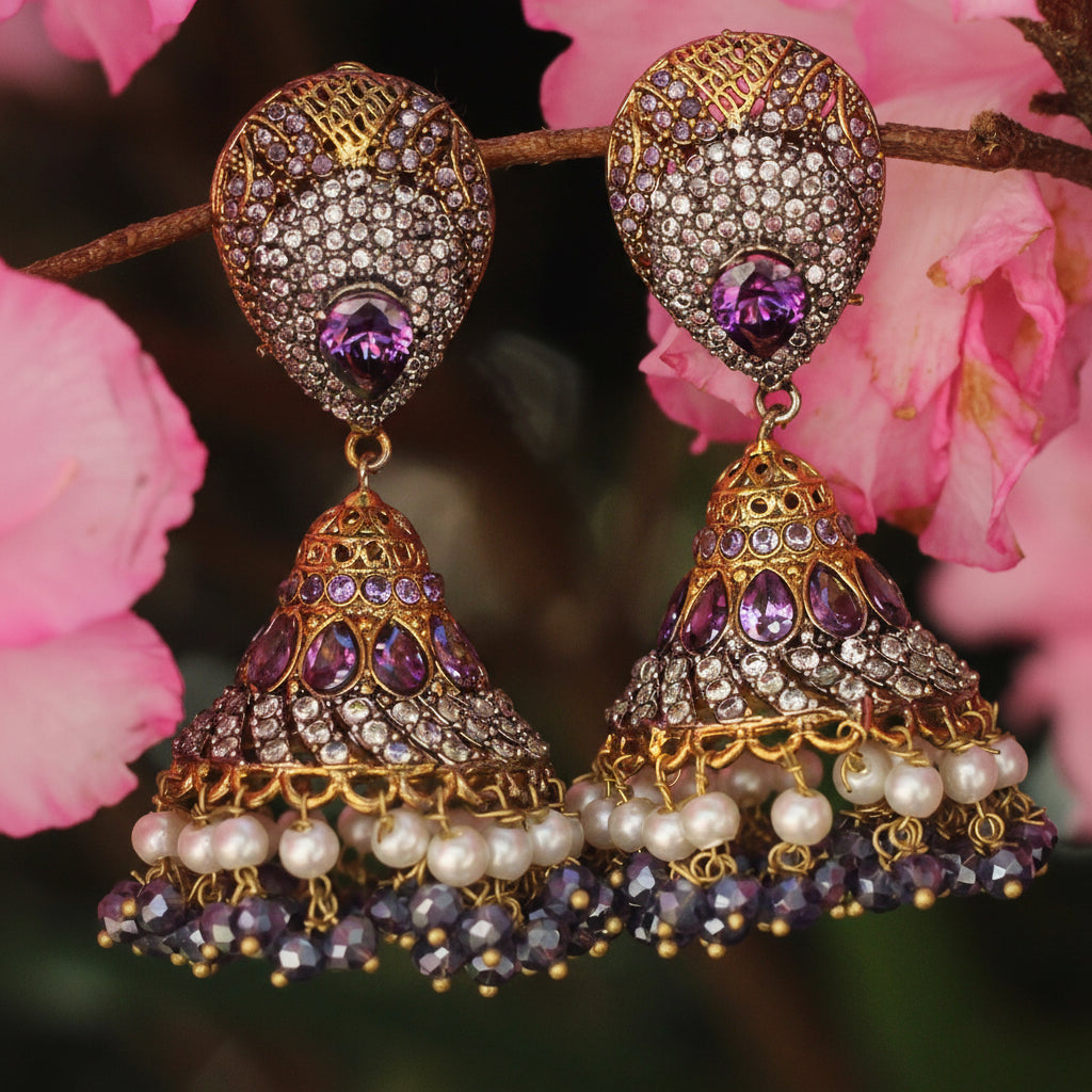Ornate earrings with purple gemstones and pearl accents against a floral background