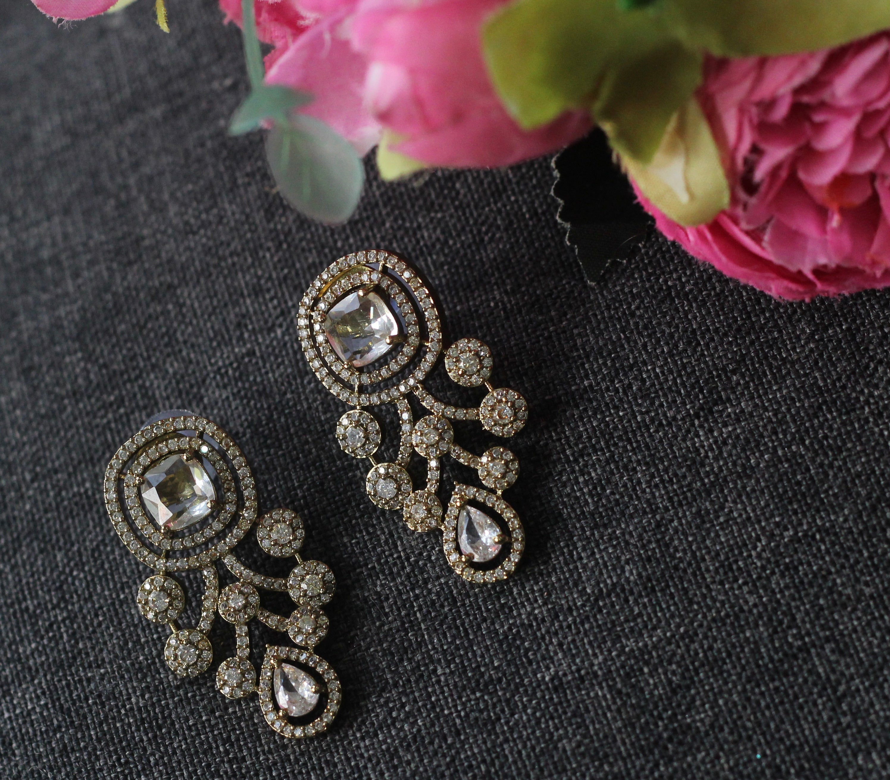A pair of ornate gold-toned statement earrings with clear crystals