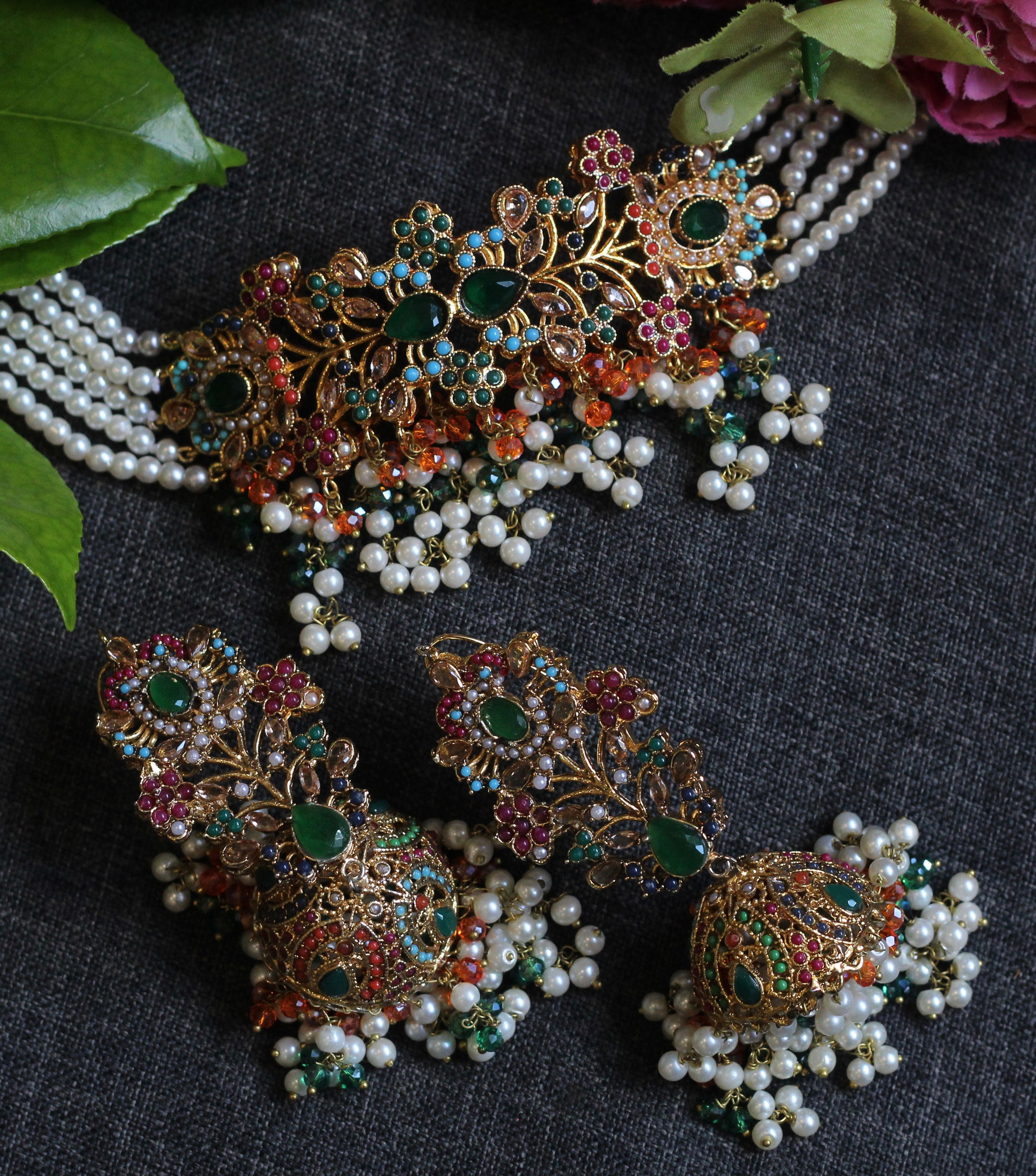 Ornate jewelry set with pearls and gemstones on a dark fabric background